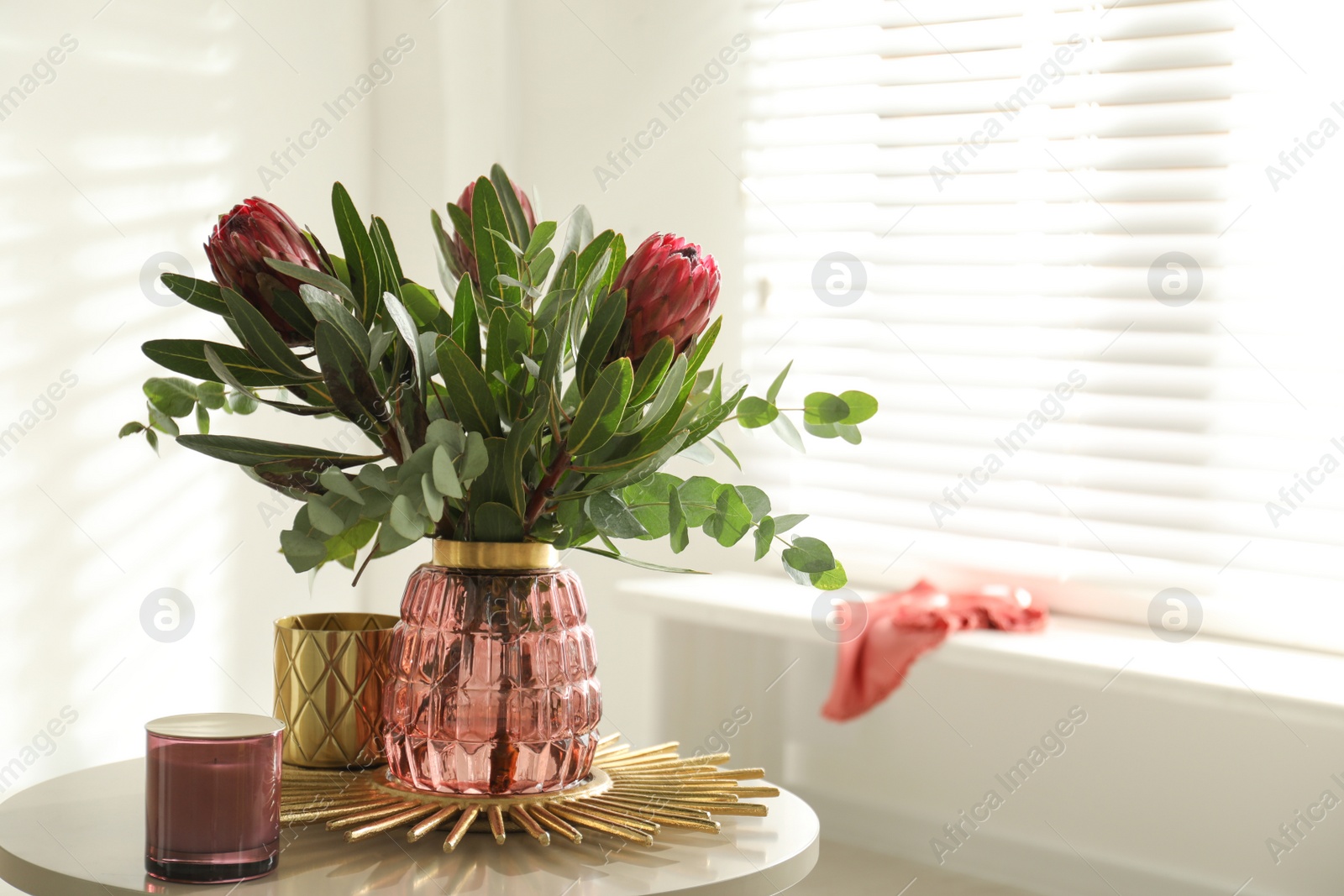 Photo of Vase with bouquet of beautiful Protea flowers on table in room