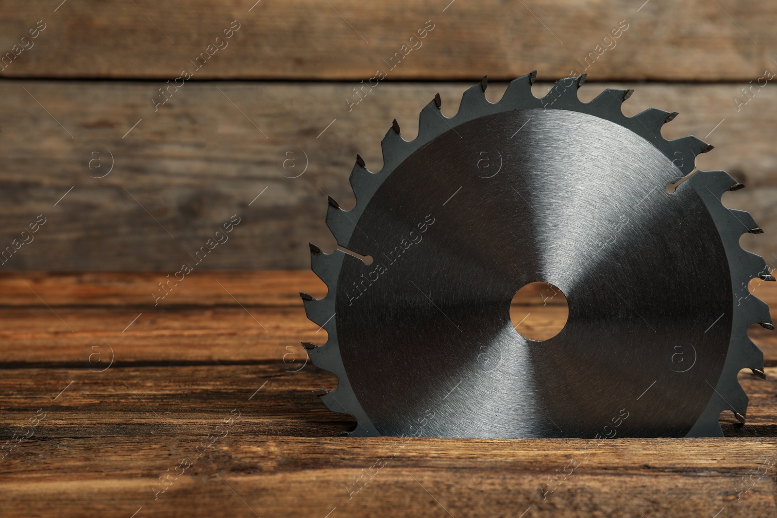 Photo of Saw disk on wooden background, space for text. Carpenter's tool