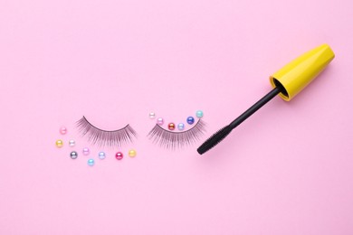 Photo of Flat lay composition with false eyelashes, colorful beads and mascara brush on pink background