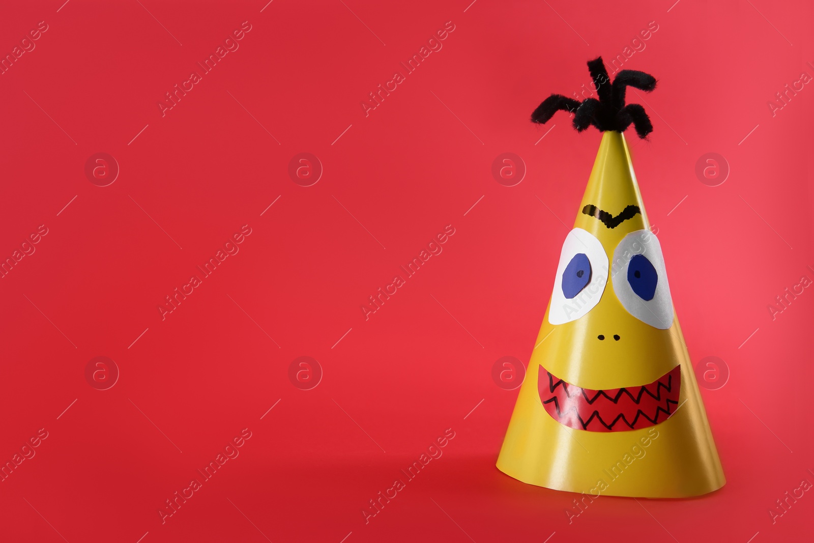 Photo of Funny yellow monster on red background, space for text. Halloween decoration