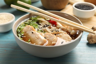 Delicious ramen with meat and ingredients on light blue wooden table, closeup. Noodle soup