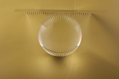 Photo of View of transparent glass ball on yellow background
