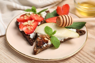 Delicious bruschettas with fresh ricotta (cream cheese), strawberry, mint and pear served with honey on wooden table, closeup