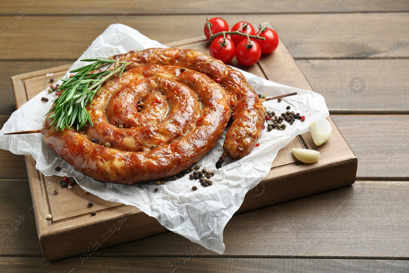 Photo of Delicious homemade sausages with spices and tomatoes on wooden table