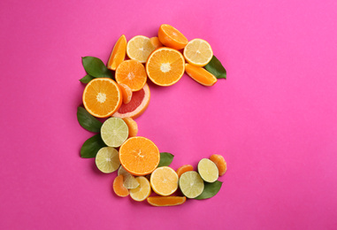 Photo of Letter C made with citrus fruits on pink background as vitamin representation, flat lay