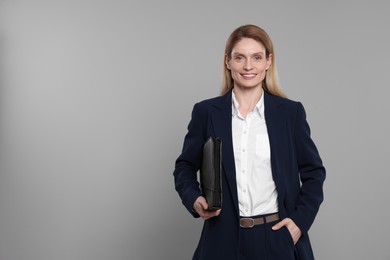 Photo of Happy real estate agent with leather portfolio on grey background. Space for text