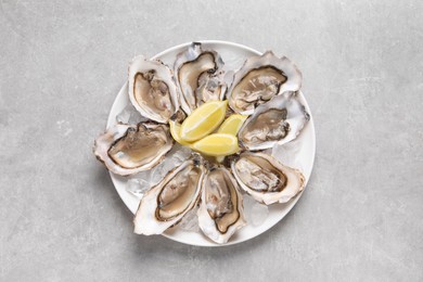 Photo of Delicious fresh oysters with lemon slices on light grey table, top view