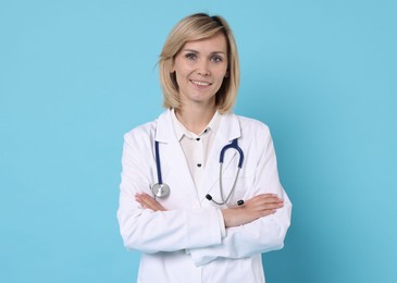 Smiling doctor with crossed arms on light blue background