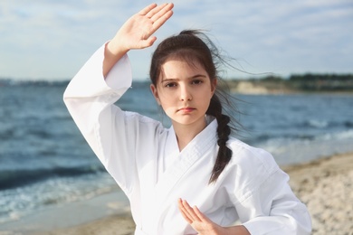 Photo of Cute little girl in kimono practicing karate near river
