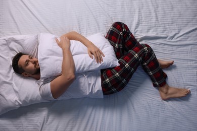 Photo of Man suffering from insomnia on bed, top view