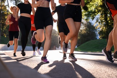 Photo of Group of people running outdoors on sunny day, closeup view