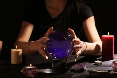Photo of Soothsayer using crystal ball to predict future at table in darkness, closeup
