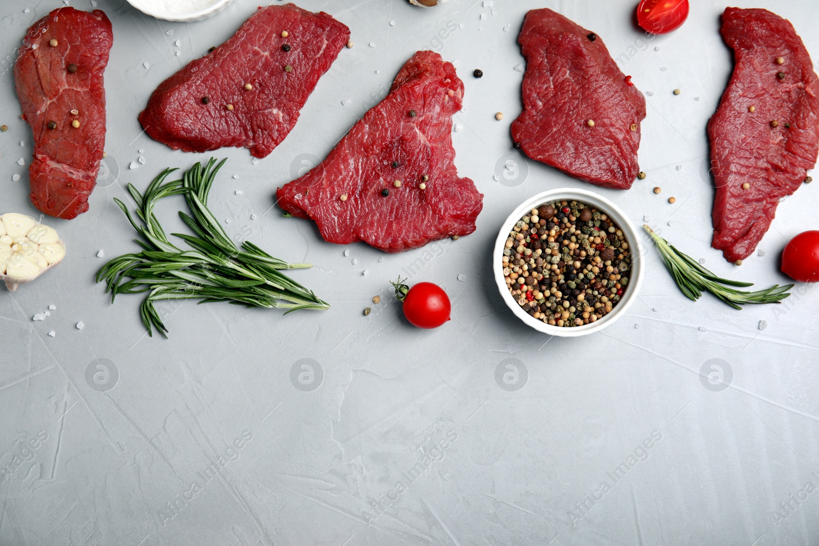 Photo of Fresh raw meat steaks and spices on light grey table, flat lay. Space for text