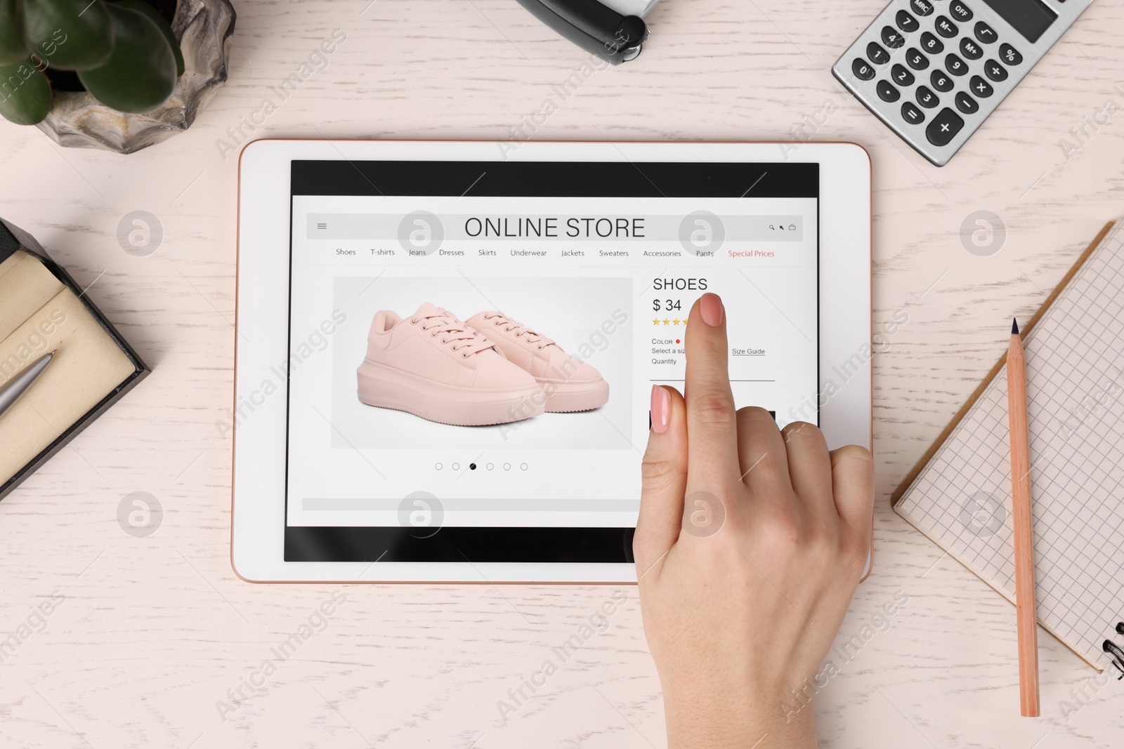 Photo of Woman with tablet shopping online at white wooden table, top view