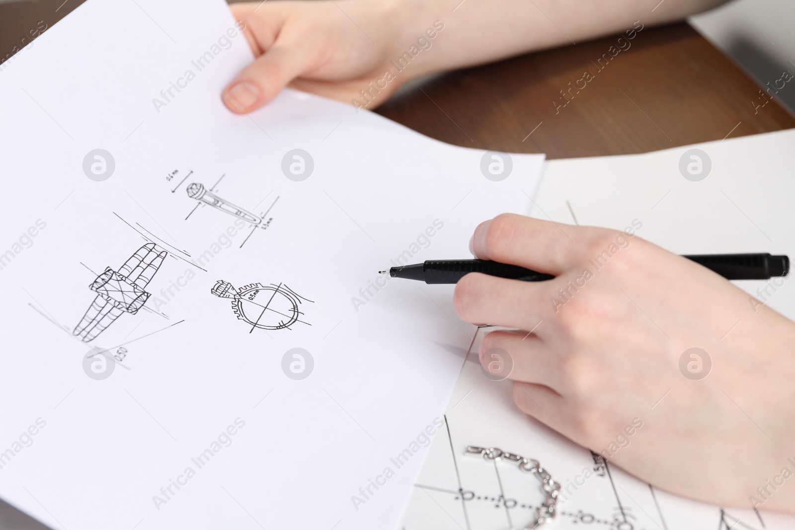 Photo of Jeweler with sketches of elegant jewelry at table, closeup