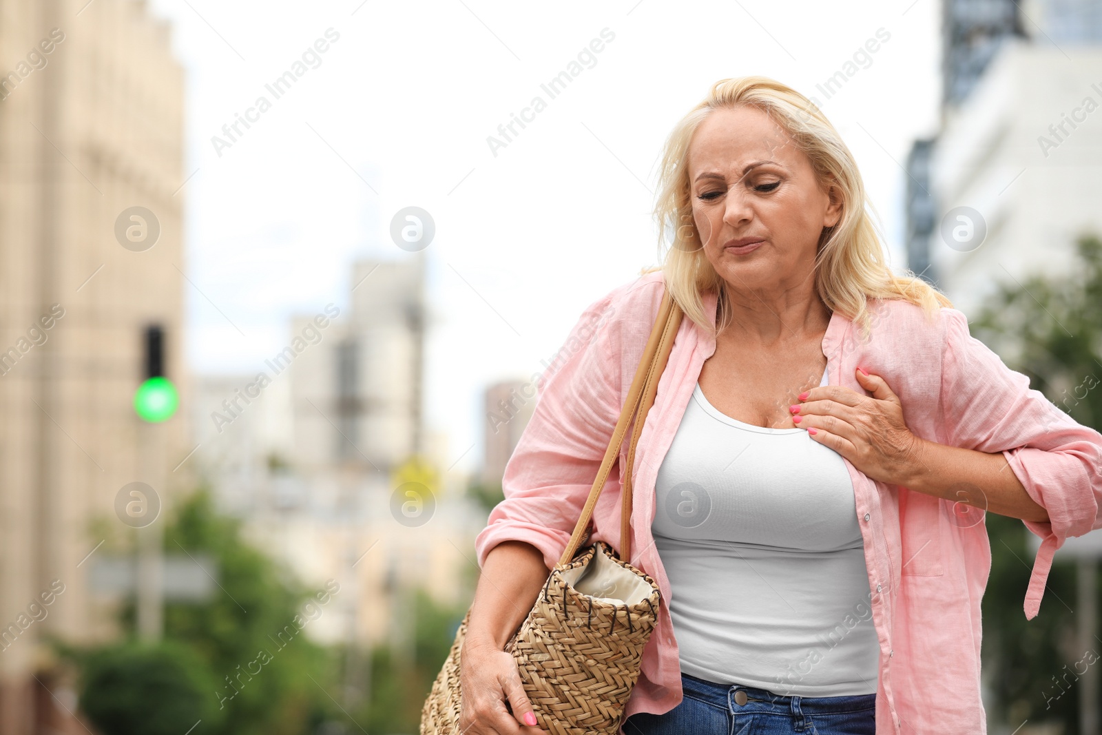 Photo of Mature woman suffering from heart attack outdoors. Space for text