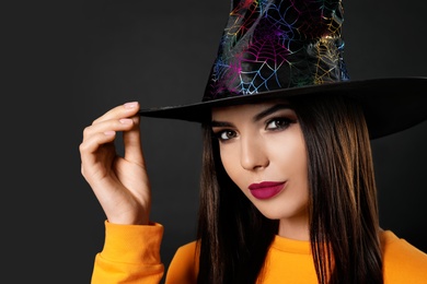 Photo of Beautiful woman wearing witch costume for Halloween party on black background