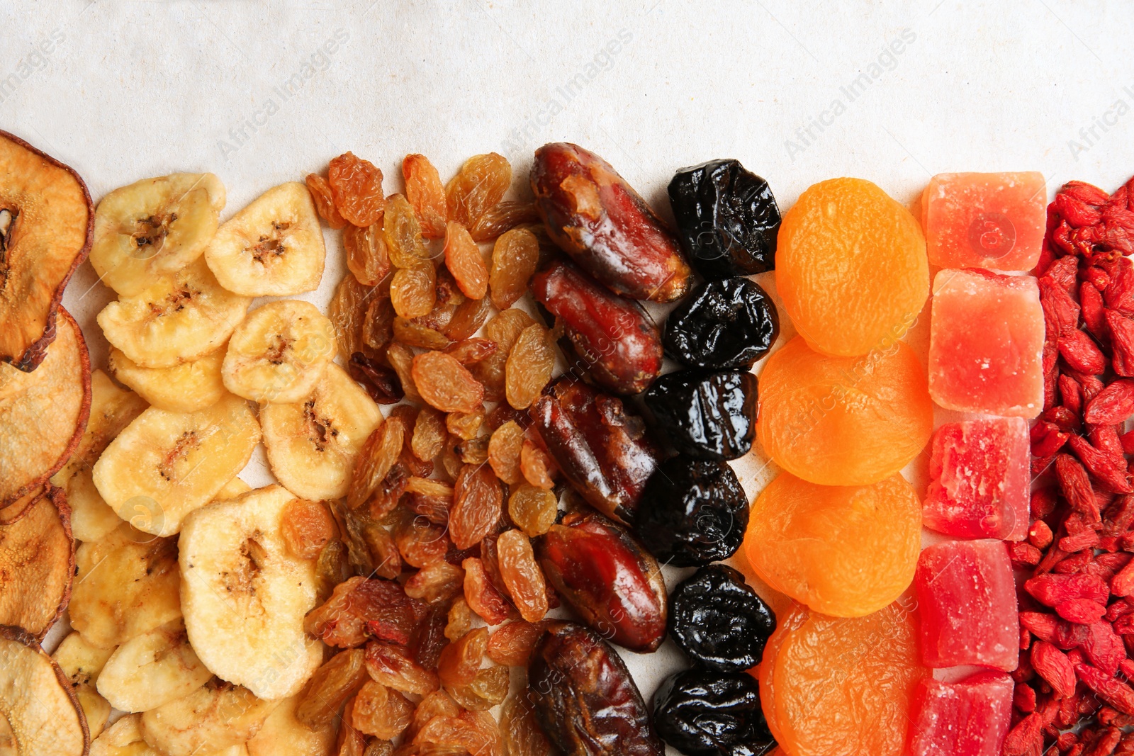 Photo of Different tasty dried fruits on paper, flat lay