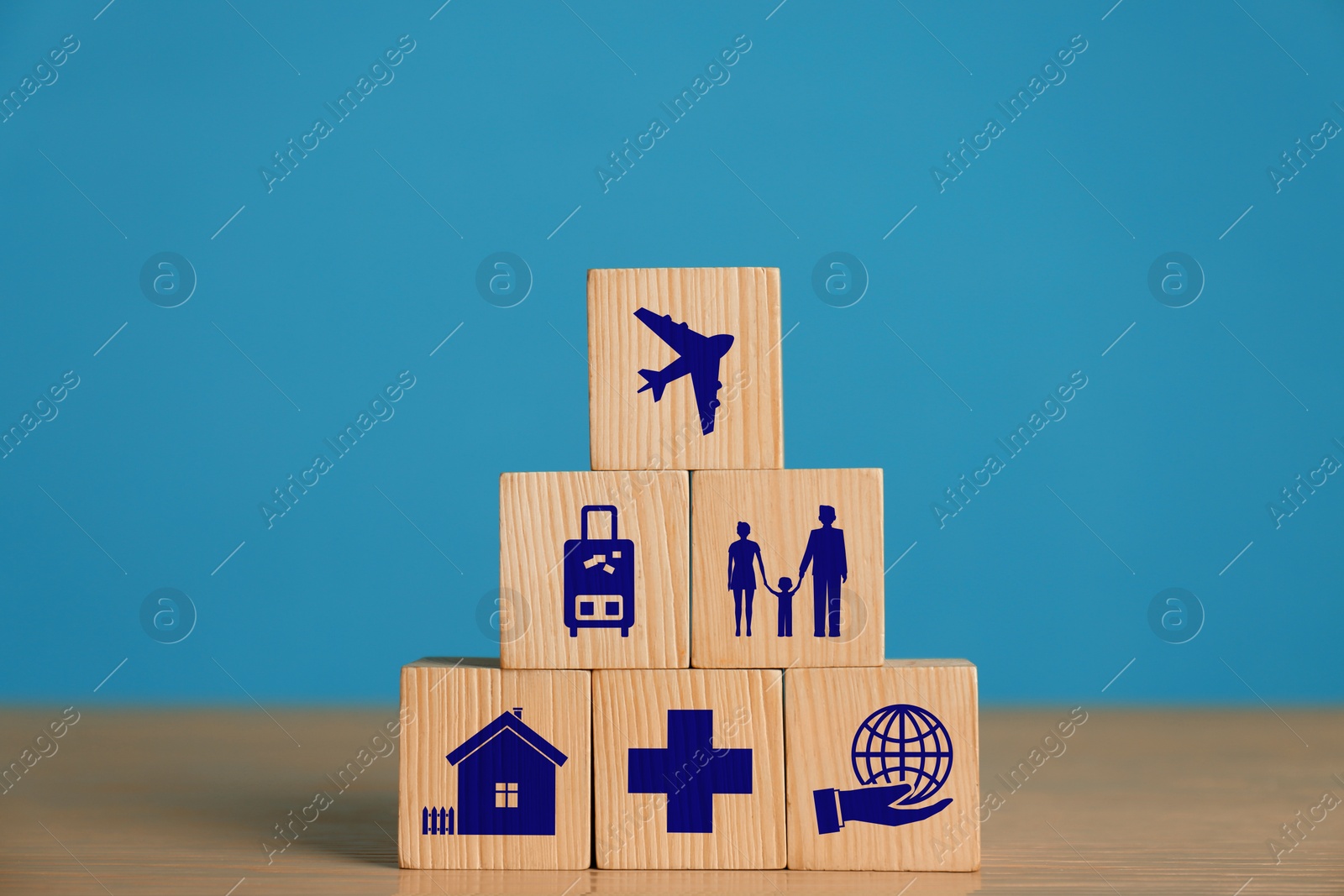 Image of Cubes with different icons on wooden table against light blue background. Insurance concept