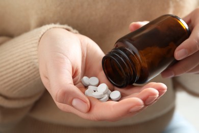 Woman pouring pills from bottle, closeup view