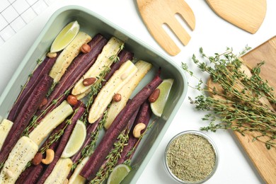 Photo of Flat lay composition with raw cut carrots in baking dish on white table