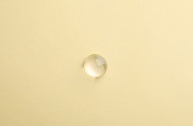 Photo of Drop of transparent ointment on beige background, top view