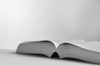 Photo of Open Bible on light table against white background, closeup with space for text. Religious book