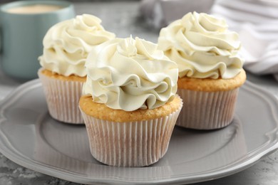 Tasty cupcakes with vanilla cream on grey table, closeup