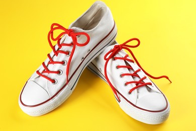 Photo of Pair of trendy sneakers on yellow background