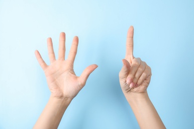 Photo of Woman showing sign six on color background, closeup. Body language