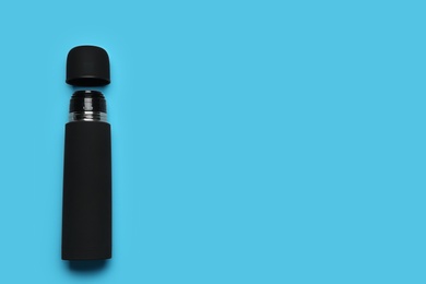 Photo of Black thermos on light blue background, top view. Space for text