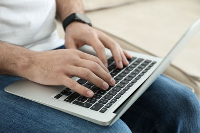 Man working on modern laptop at home, closeup