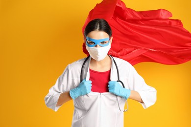 Photo of Doctor dressed as superhero posing on yellow background. Concept of medical workers fighting with COVID-19