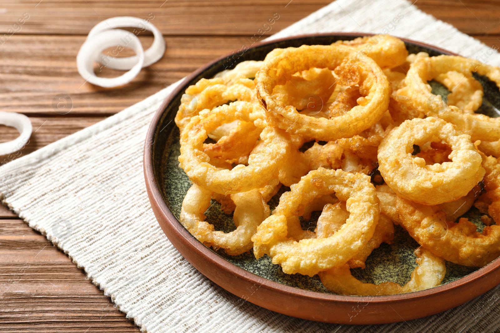 Photo of Homemade crunchy fried onion rings on wooden table, closeup