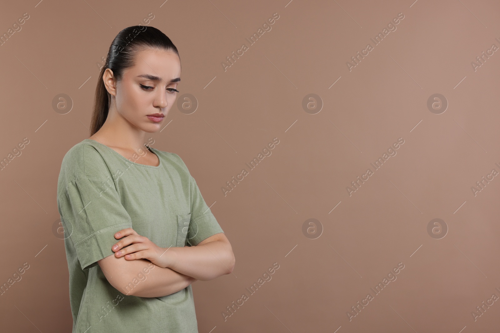 Photo of Portrait of resentful woman with crossed arms on brown background. Space for text