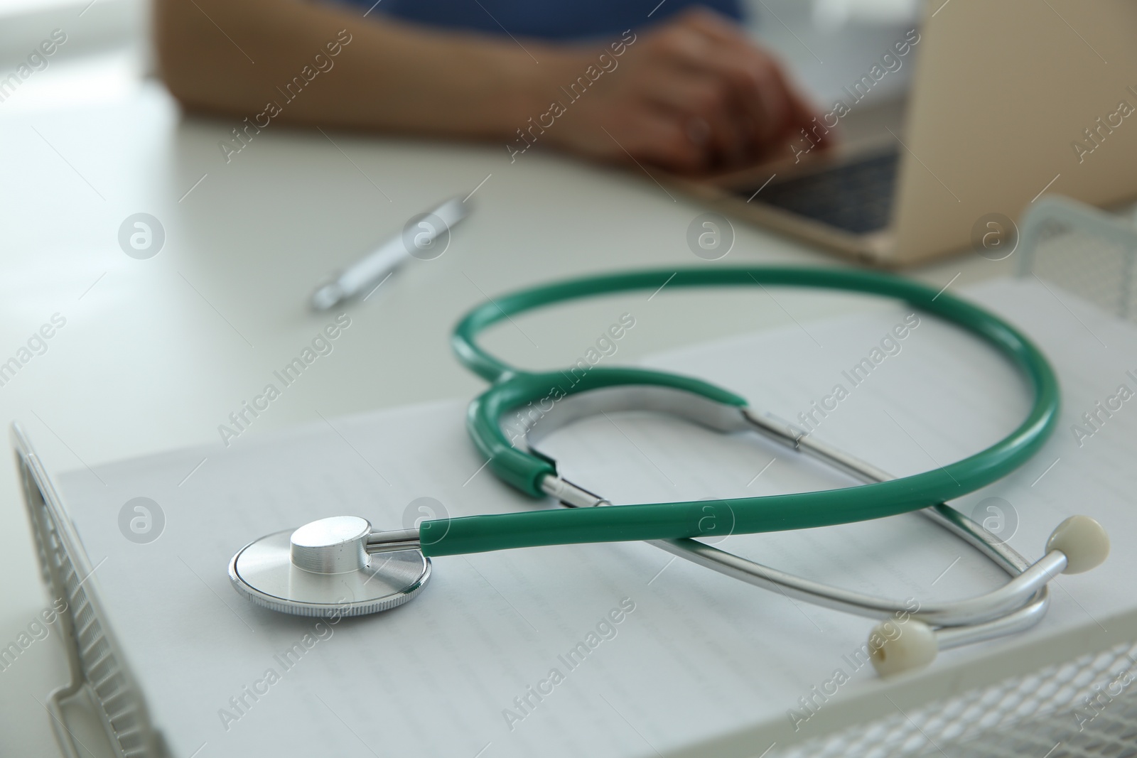 Photo of Doctor at white table in hospital, focus on medical stethoscope