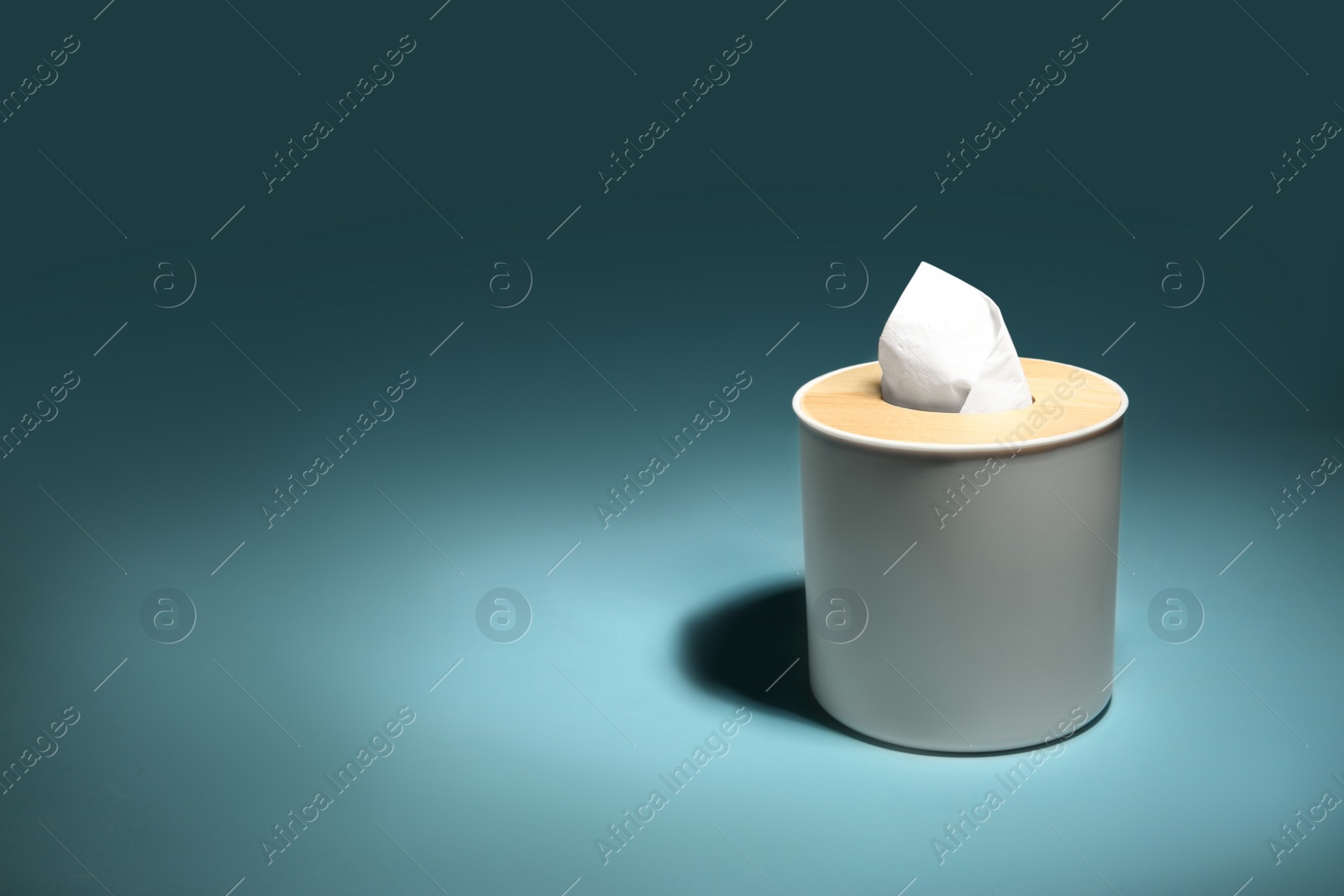 Photo of Holder with paper tissues on blue background. Space for text