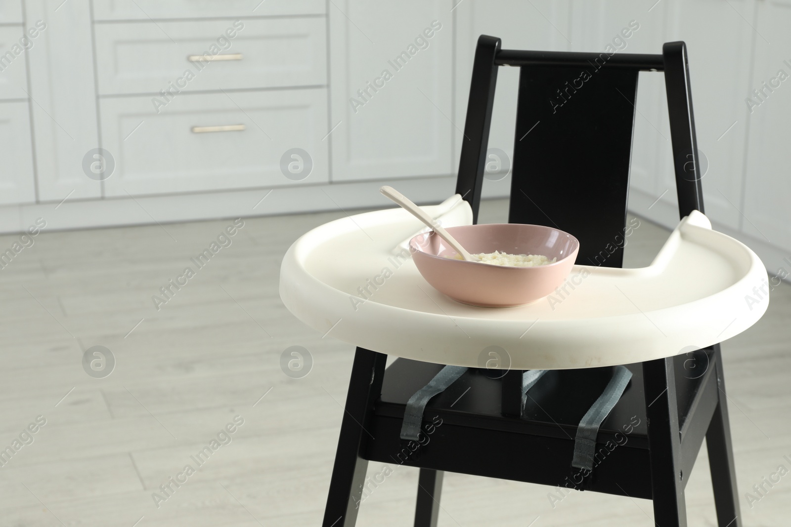 Photo of Baby high chair with healthy food in kitchen. Space for text