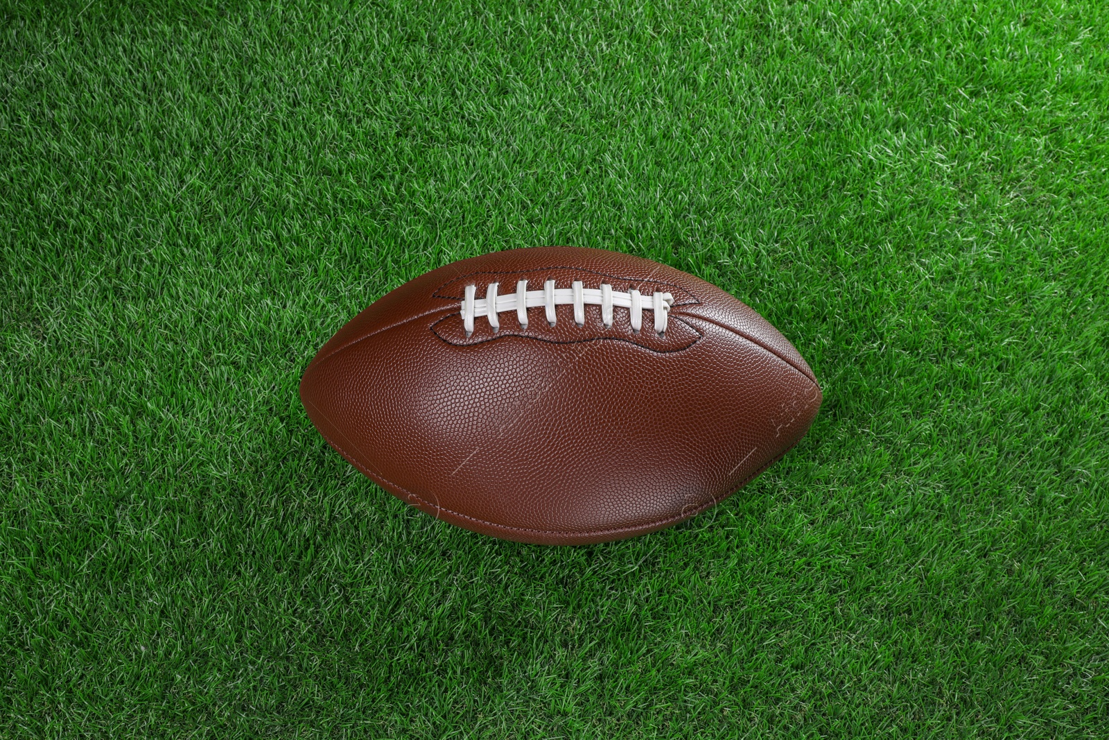 Photo of Leather American football ball on green grass