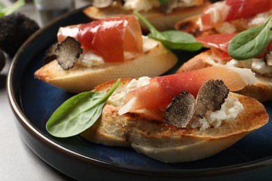 Photo of Delicious bruschettas with cheese, prosciutto and slices of black truffle on table, closeup
