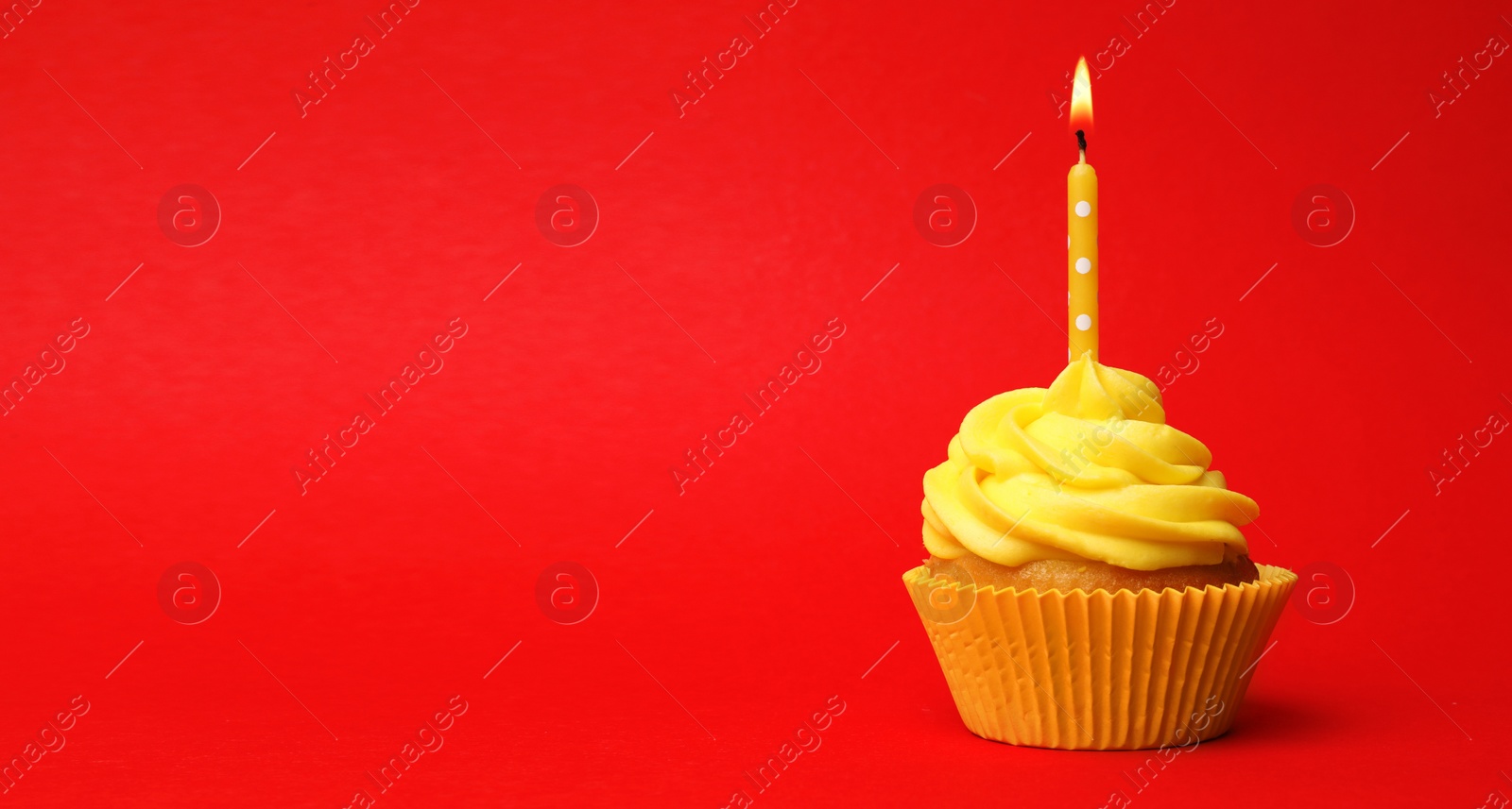 Photo of Delicious birthday cupcake with yellow cream and burning candle on red background. Space for text