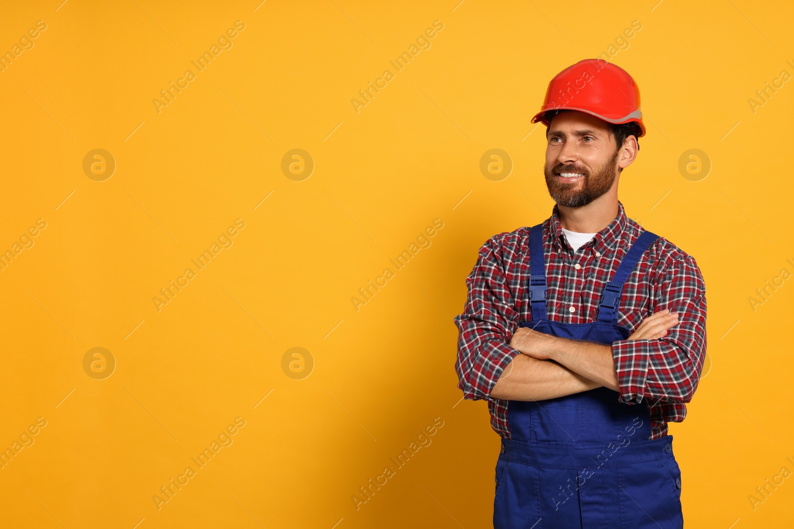 Photo of Professional builder in uniform on yellow background, space for text