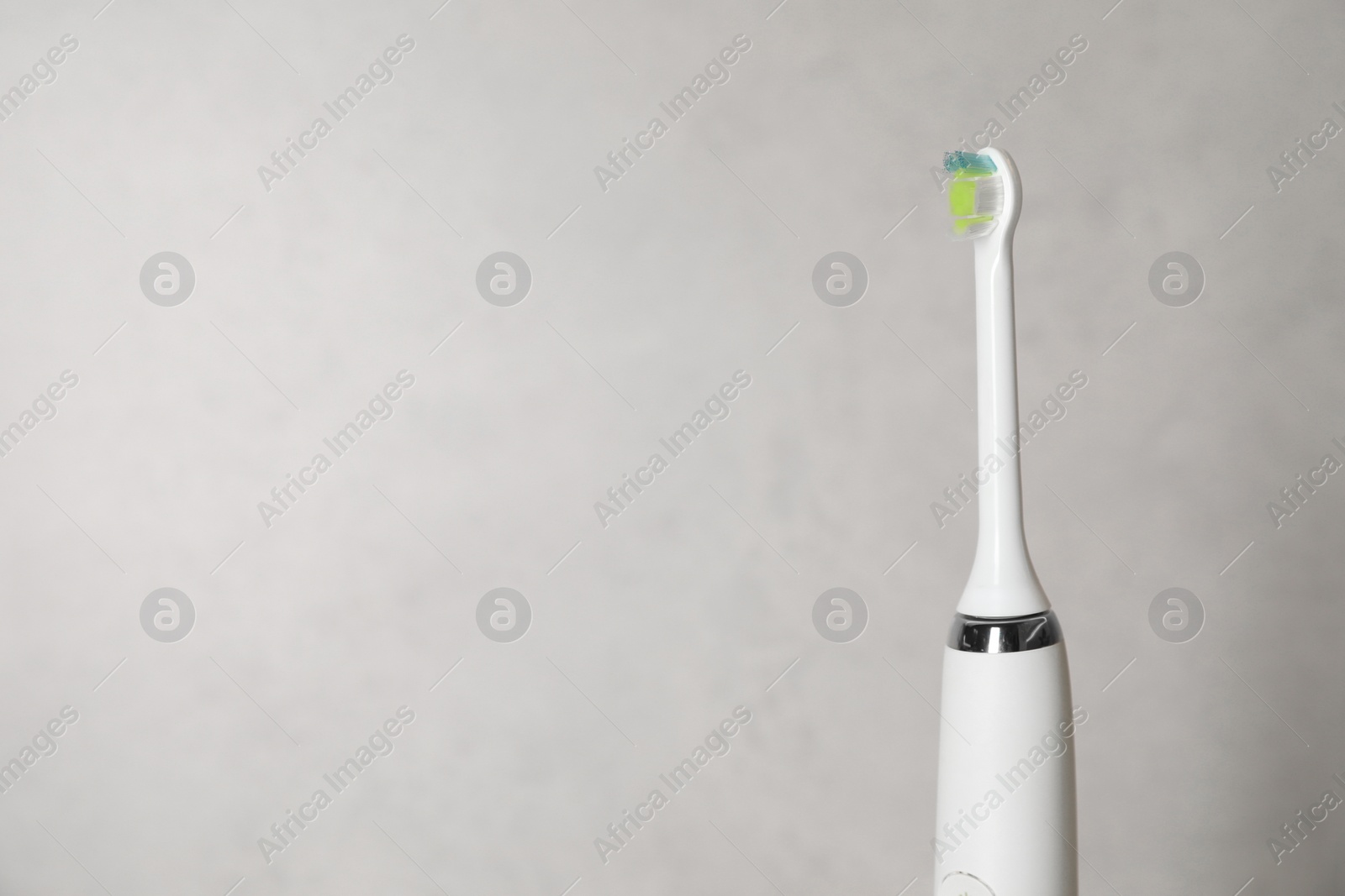 Photo of Electric toothbrush on light background, space for text