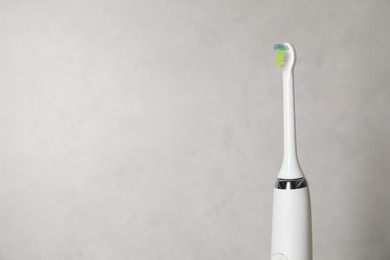 Electric toothbrush on light background, space for text