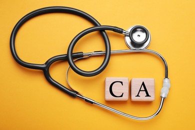 Photo of Stethoscope and calcium symbol made of wooden cubes with letters on orange background, flat lay