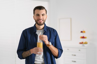 Handsome man with delicious smoothie at home. Space for text