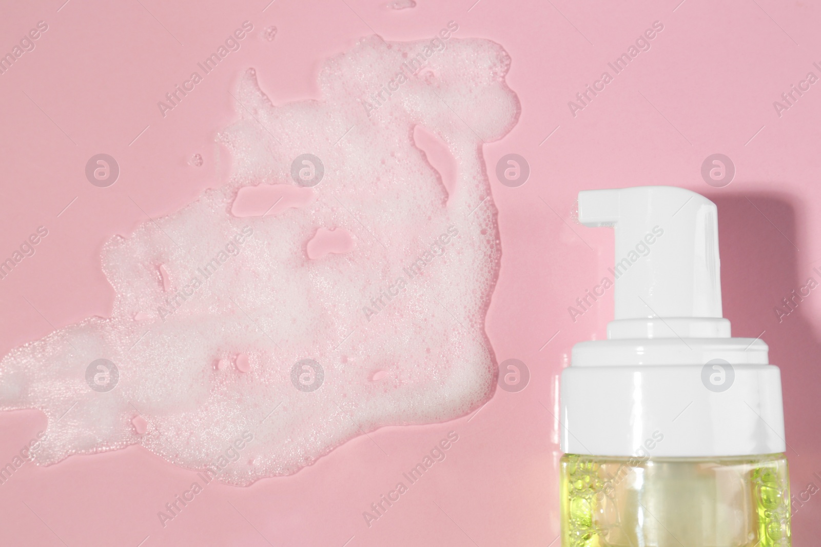 Photo of Bottle with cleansing foam on pink background, flat lay. Cosmetic product