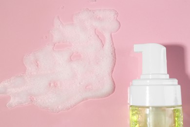 Photo of Bottle with cleansing foam on pink background, flat lay. Cosmetic product