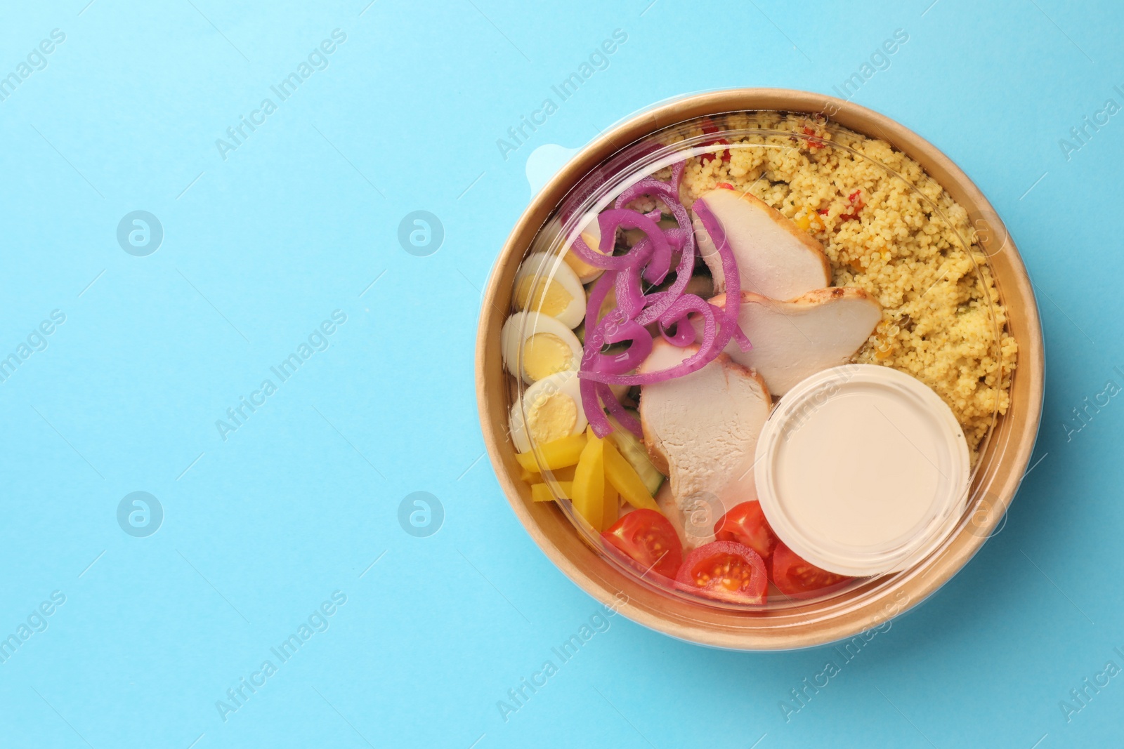 Photo of Tasty food in container on light blue background, top view. Space for text