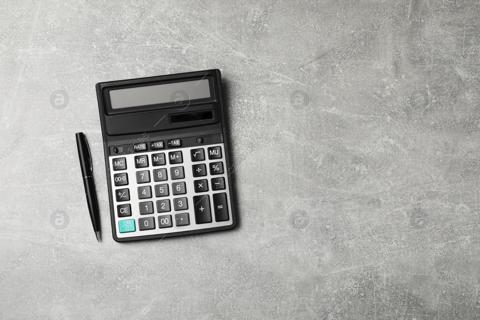 Photo of Calculator and pen on grey table, top view. Space for text